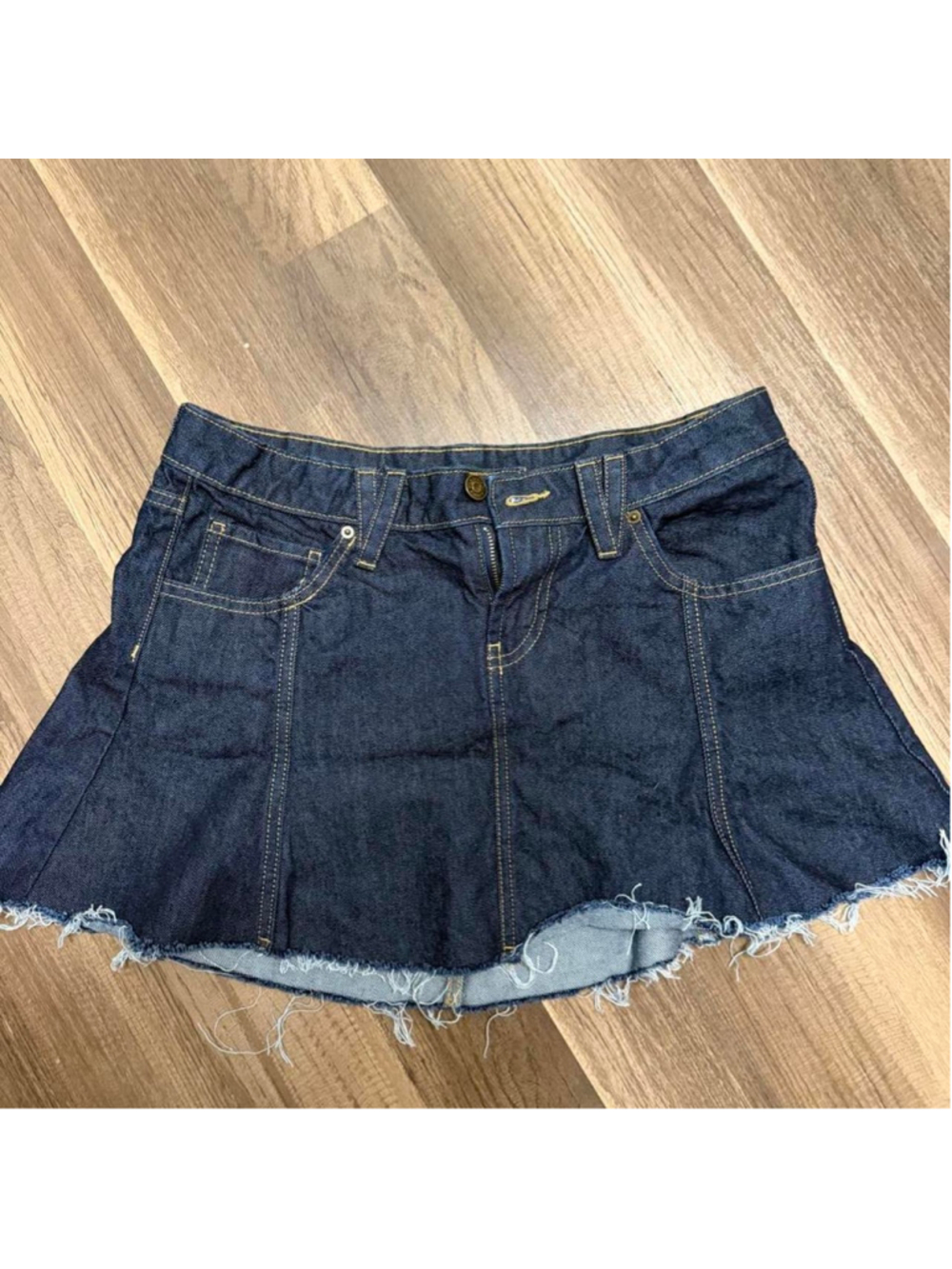Dark wash denim micro mini skirt with a flared Y2K-inspired silhouette, raw fray